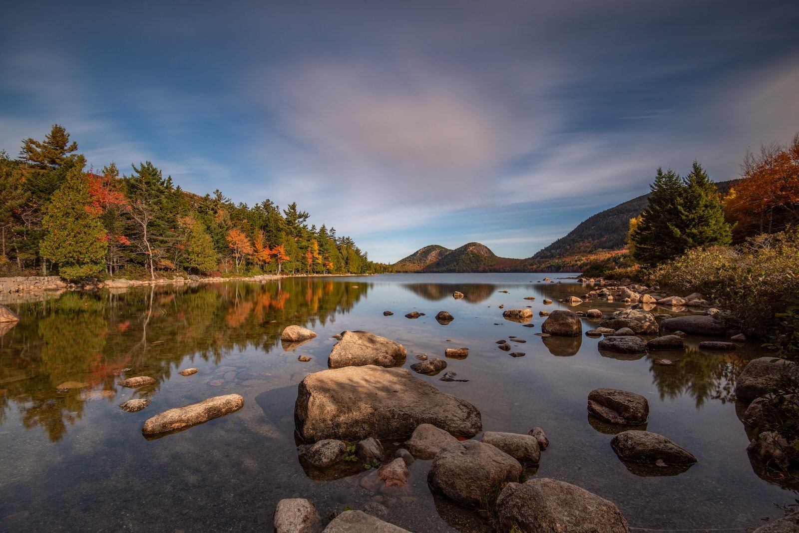 Autumn foliage reflected in a rocky lake surrounded by mountains in Acadia National Park, Maine