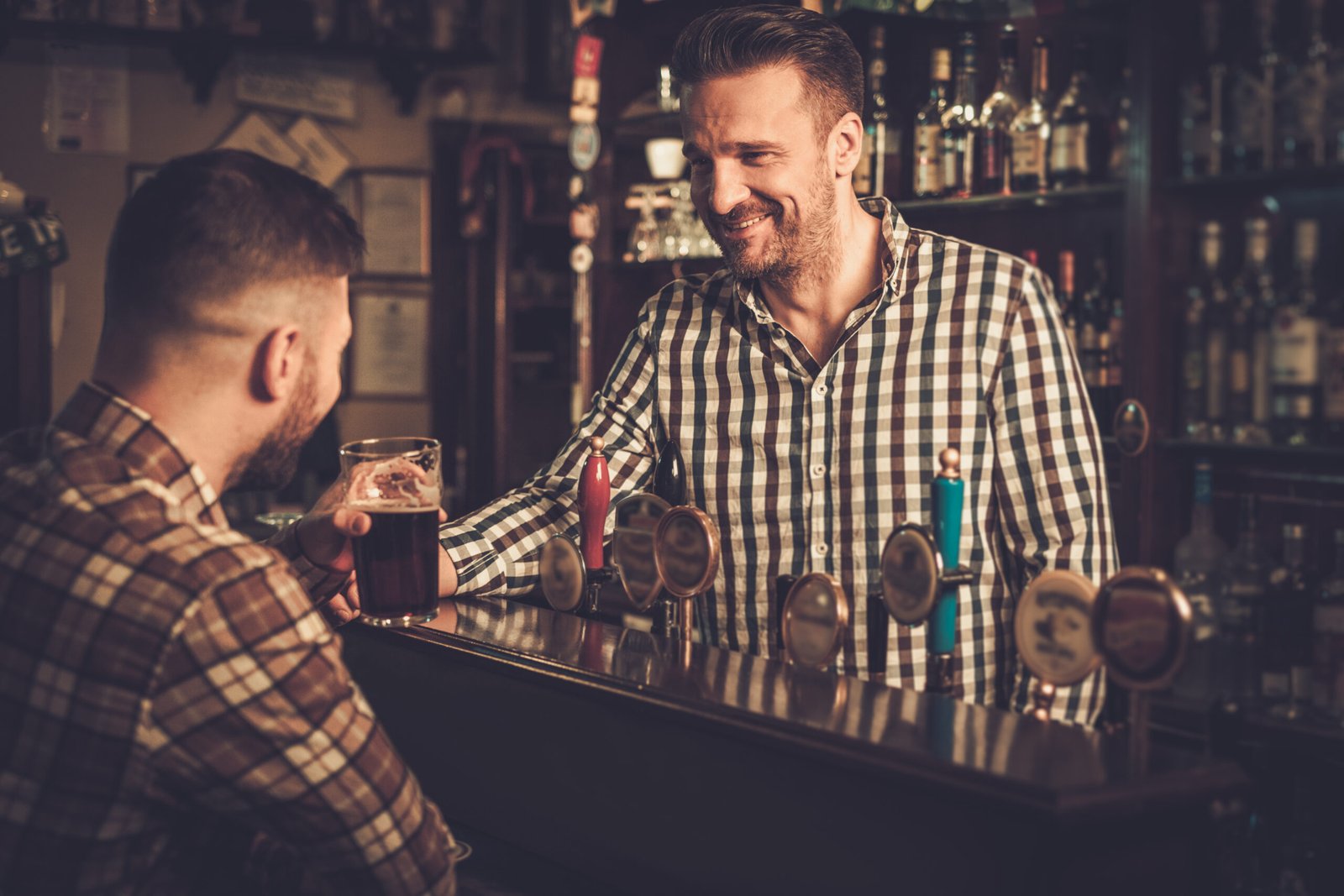 Man talking with a bartender inside a traditional pub