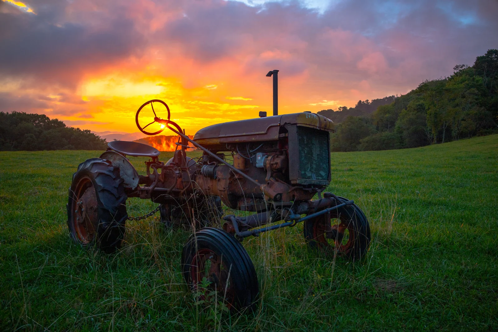 Vintage farm tractor in an Appalachian mountain field at sunrise
